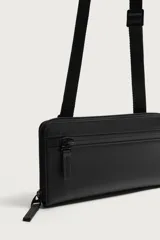Bandolera rectangular de acabado engomado con cierre de cremallera en el compartimento principal y bolsillo interior con cierre. Incluye asa de hombro ajustable y extraíble.