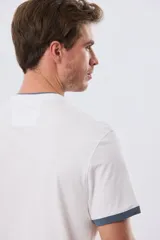 Remera blanca de manga corta con cuello mao y cierre frontal parcial con tres botones. Presenta detalles en color azul en el cuello y en los bordes de las mangas, además de un pequeño logo bordado en el pecho.