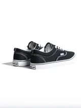 Championes de lona color azul grisáceo, estilo skate o casual, con cordones blancos y suela de goma blanca con una línea fina azul en el borde.