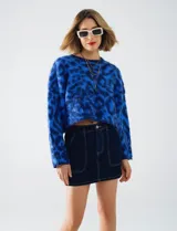Buzo de lana con cuello redondo, manga larga amplia y corte crop. Presenta un estampado animal print en tonos de azul vibrante.