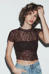 Top crop semitransparente de encaje negro, con cuello redondo y manga corta.