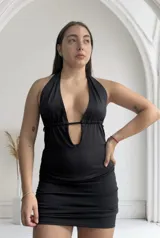 Minivestido negro con escote halter y abertura en el abdomen.