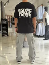 Remera oversize blanca de manga corta, con gran estampado negro en la espalda con la palabra 'Peace' y símbolos gráficos.