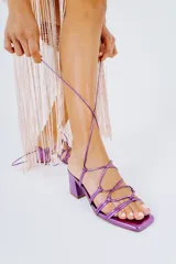 Sandalias de tacón cuadrado color fucsia metalizado, con tiras finas que se atan alrededor del tobillo.