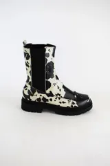 Bota tipo chelsea de cuero acharolado negro, con elásticos laterales y suela track dentada.