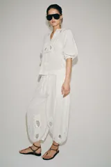 Camisa blanca de algodón con escote en pico, mangas por debajo del codo y detalles de bordados y encaje a tono en el pecho y las mangas.