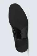 Zapato de vestir tipo derby de cuero negro brillante, con cordones y suela con ligero tacón.