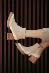 Botín de cuero color beige con puntera charolada, cierre lateral con cremallera y tacón ancho de madera.