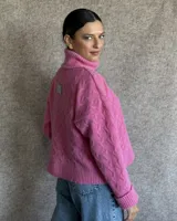 Sweater de lana color crudo con cuello alto y diseño trenzado.