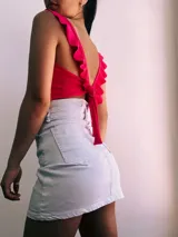 Crop top negro con textura brillante, breteles anchos con volados y espalda descubierta que se ata con lazos.