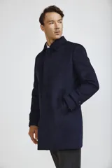 Abrigo tipo carcoat de corte clásico y estructura formal, en color azul marino. Presenta cierre frontal con botones, cuello camisero y bolsillos laterales. El interior cuenta con un forro oscuro con detalles en contraste.