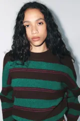 Jersey de punto con diseño de rayas horizontales en tonos marrón, verde y fucsia. Presenta cuello redondo, manga larga y terminaciones en rib.