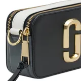 Cartera bandolera Marc Jacobs modelo The Snapshot, color tostado con herrajes dorados y logo frontal metálico. Incluye correa ajustable con diseño de cinta tejida y cierre superior.