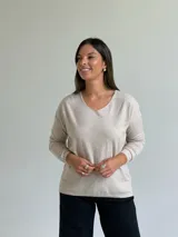 Sweater de punto fino en color beige, con escote en V y mangas largas con puños ajustados.