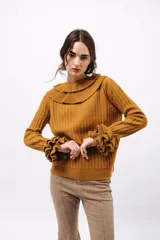 Buzo de tejido acanalado color lila, con cuello redondo decorado con dos volados y mangas largas con tres volados pequeños en los puños.