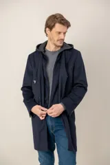 Chaquetón de lana color azul marino, con diseño de doble capa que incluye una capucha integrada y cierre frontal. Presenta solapas clásicas y corte recto.