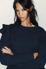 Jersey de punto color azul marino, con cuello redondo, manga larga y volantes decorativos en el frente y los hombros.