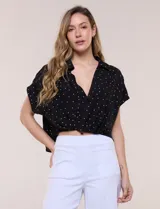Blusa crop cruzada Allie Rose de tela liviana negra con estampado de lunares blancos, escote en V y cuello camisero.