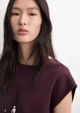 Top de punto fino color bordó, de diseño recto, cuello redondo, mangas cortas y cierre delantero con tres botones.