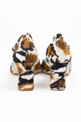 Zapatos de tacón con estampado animal print en tonos marrón, blanco y negro. Tienen punta fina, pulsera con hebilla lateral y tacón ancho. Interior de piel y suela de cuero.