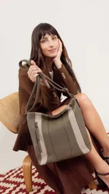 Cartera bandolera color marrón con detalles en gamuza. Tiene correa regulable, cierre metálico frontal y trasero, y división interna.