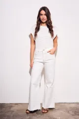 Remera blanca de algodón con textura de puntos calados horizontales, corte al cuerpo y mangas cortas tipo mariposa.