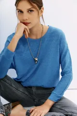 Remera azul de algodón peruano con textura jaspeada, de moldería holgada y buena caída, con mangas largas que se ajustan hacia la muñeca y se ensanchan debajo del brazo.