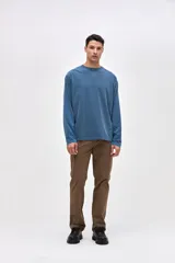 Remera de manga larga color beige, confeccionada en algodón lavado con textura suave. Presenta cuello redondo con detalle de costura en V, corte clásico y estampado pequeño en el pecho con la palabra Uniform.