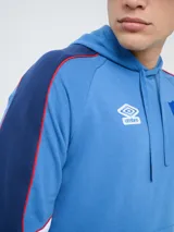 Canguro deportivo Umbro del Club Nacional de Football, modelo Nexo para hombre. Diseño en color azul marino con mangas rojas y detalles en celeste y blanco, capucha con cordón ajustable y bolsillo tipo canguro.