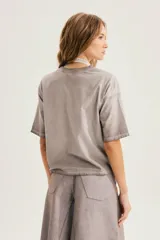 Remera gris de corte relajado, con cuello redondo, mangas cortas y pequeño estampado en el pecho.