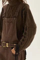 Overol de jean color marrón con calce barrel, tiro medio, pierna ancha y redondeada que termina a la altura del tobillo.