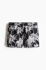 Short de baño con estampado de palmeras en blanco y negro, cintura elástica con cordón ajustable, bolsillos laterales y suspensor interior de malla.