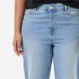 Jean de corte bootcut con cintura alta y cierre frontal con botón y cremallera. Presenta un diseño de cinco bolsillos y un acabado deshilachado en el bajo.