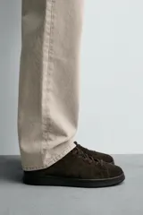 Zapatilla de cordones confeccionada en piel con acabado de serraje, de horma redonda y suela a tono.