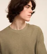 Remera color crema, de corte holgado, con cuello redondo y mangas cortas.