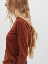 Camiseta negra de manga larga, con tejido acanalado, cuello redondo a la base y corte tipo crop. Presenta costuras rojas a la vista y un logo "M" bordado en rojo en el lateral izquierdo.