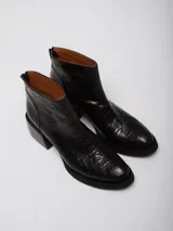 Conjunto de dos piezas compuesto por una musculosa de cuello redondo y un pantalón de corte recto, ambos en color negro. El pantalón incluye un cinturón ancho con hebilla metálica circular.