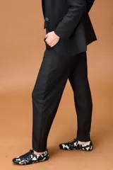 Pantalón sastrero de corte ancho y tiro alto, con diseño de líneas limpias, bolsillos laterales y cierre frontal con botón. Presenta una caída fluida y estructura amplia.