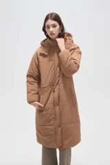 Campera larga tipo parka acolchada color negro, con capucha desmontable, cierre frontal con botones a presión, bolsillos laterales y cordón ajustable en la cintura.