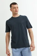 Remera de manga corta color azul oscuro o negro deslavado, con cuello redondo y corte raglán. Presenta un pequeño estampado en relieve o tono sobre tono en el pecho con texto y un símbolo.