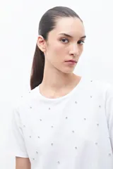 Remera blanca de algodón con cuello redondo y apliques de strass plateados.