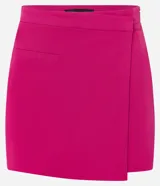Short pollera corto en bengalina color fucsia, con superposición asimétrica en el delantero y pequeño bolsillo. Cierre lateral con cremallera.