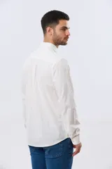 Camisa de lino de manga larga en color beige, con cuello camisero, cierre frontal de botones y un bolsillo ojal en el pecho.