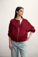 Chaqueta tipo bomber color bordó, con cierre frontal metálico, cuello redondo y puños elásticos.