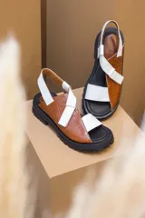 Sandalias de plataforma con suela track, confeccionadas en una combinación de cuero liso y cuero con textura croco. Presentan tiras anchas en el empeine y cierre con hebilla ajustable en el talón.