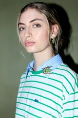 Prendedor dorado con forma de escarabajo, que presenta un cuerpo central de resina o cristal verde translúcido.