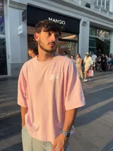 Remera rosa de corte holgado con estampado trasero de la palabra "Ittai" en blanco con una estrella.