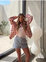 Chaqueta ligera de color amarillo con estampado de lunares negros, cuello alto, mangas largas anchas y cordón ajustable en el dobladillo inferior.