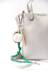 Llavero para bolso con dijes de guante, bate y pelota de béisbol, unidos por un cordón trenzado verde y blanco.