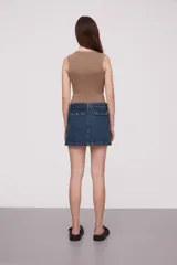 Falda corta de jean color beige claro, de corte al cuerpo, con tiro bajo y bolsillos cargo grandes y planos en los laterales.